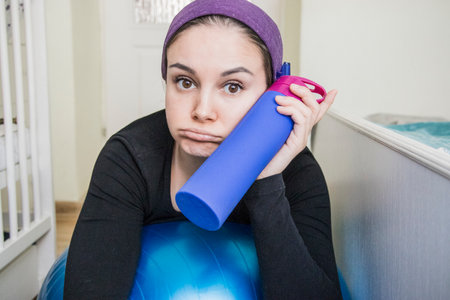 woman in a scarf on a fitness ball smiling, home sports, training in living room.の写真素材