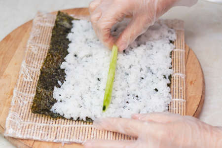step 1. Cook's hands close-up. A chef makes sushi and rolls from rice, red fish, avocado and philadelphia cheese. step by stepの写真素材
