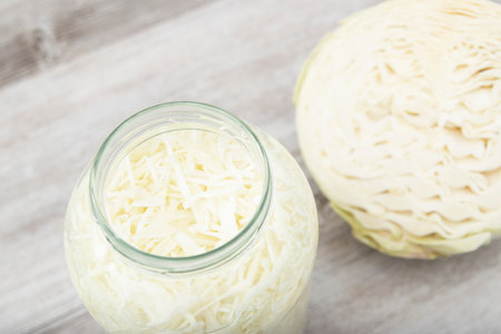 Sauerkraut in open glass mason jar. The best natural probiotic. Pickling cabbage at home on table. Homemade kraut, copy space for text.の写真素材