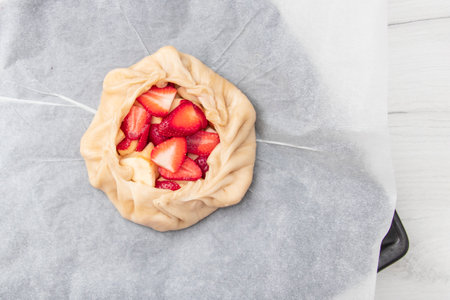 Apple strawberry pie, top view side border against a rustic wood background with copy space. Autumn food concept. Step by step recipe galetteの写真素材