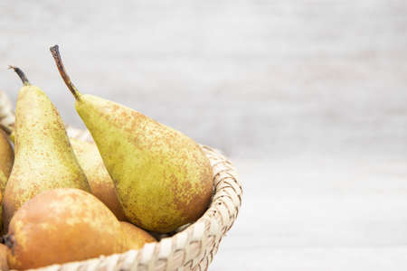 Ripe juicy pears in wicker basket on wooden table, top view, harvest for delicious juiceの写真素材