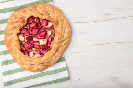 French galette or pie with strawberries and almonds on baking paper on a culinary background top view. Summer homemade sweet pastriesの写真素材