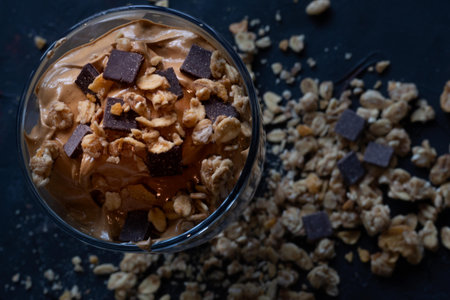 glass of milk with creamy coffee with cereal muesli and chocolate chips on a dark background