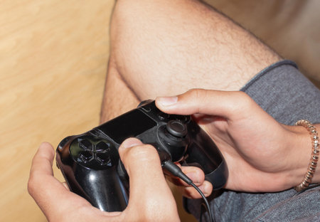 young man in shorts playing with the control of the videoconsole to modern games