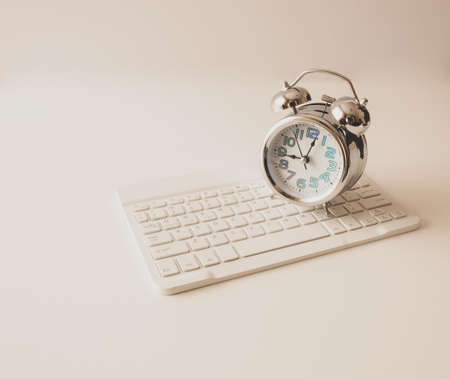 analog clock on wireless computer keyboard on white backgroundの写真素材