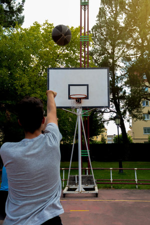 boy shooting hoops on an outdoor court in a park