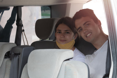 young teenage siblings sitting in the van to take a trip with the family on a summer dayの写真素材