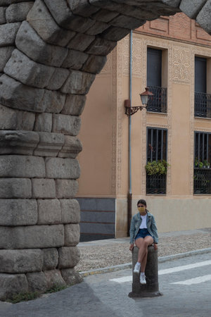 girl sitting on a stone column under an ancient arch in a Roman city on a summer dayの写真素材