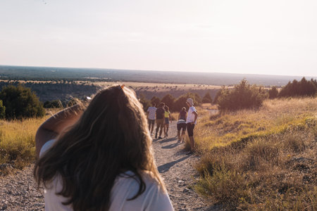 group of young people walking through the countryside and the mountains on a sunny day