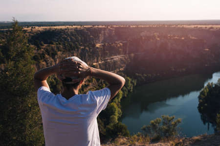 young man with his hands on his head in a relaxed position and enjoying the views of the landscape of the Natural Park Hoces del RÃ­o DuratÃ³n located in Segovia in Spain on a sunny dayの写真素材
