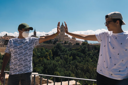 two young men hold with their hands the Cathedral of Segovia in a creative photo from the Alcazar of that town in Spain in a sunny dayの写真素材