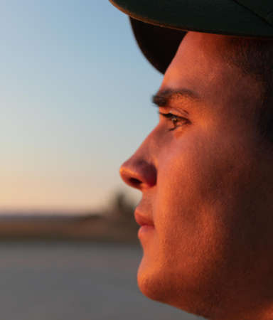 young teenager with hat facing sideways and the evening sun hitting her face with copy spaceの写真素材