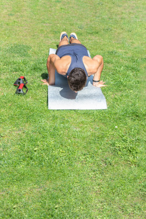 young man running training with a push-up on a mat on a sunny day in the garden