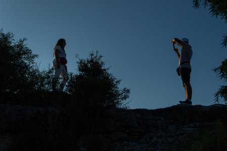 young couple taking pictures at the top of the mountain on a summer day