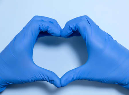 doctor or nurse with blue latex gloves creating a heart with copy space for health protection love and careの写真素材