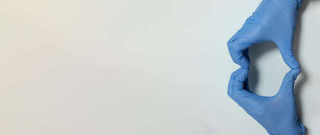 gesture of a doctor or nurse wearing blue latex gloves creating a heart with copy space for health protection love and care in the face of Covid19 or pandemicの写真素材