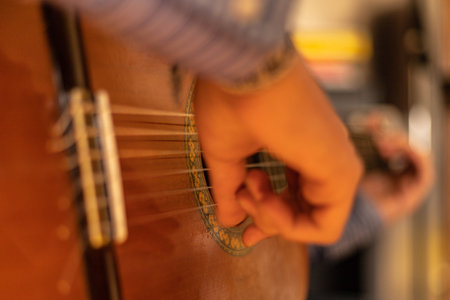 selective focus on a moving hand of a person learning to play the classical guitar