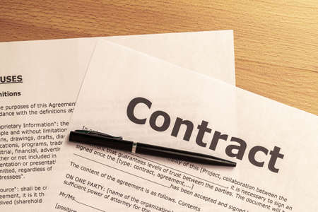detail of a drafted contract ready to be filled out and signed by a customer on a wooden business concept tableの写真素材