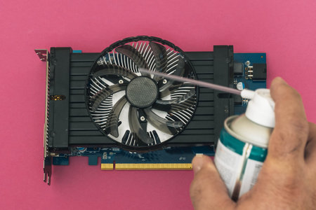 selective focus of a pc graphics card being cleaned with a can of cold compressed air computer...