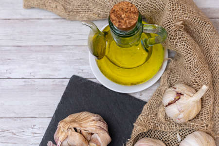 Oil in a jar together with garlic on burlap and slate board to prepare aromatic condiments with copy space.の写真素材
