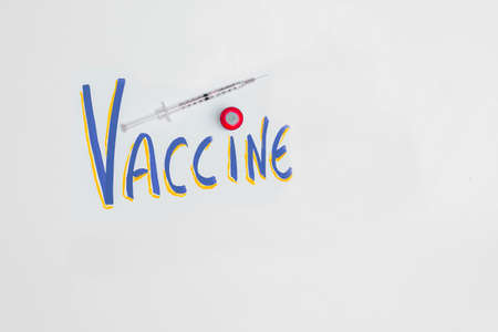 Poster with the letters Vaccine and a canister with the syringe for Covid19 and other viruses as the end of the disease having copy space and in concept of health and pandemic.の写真素材