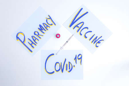 Poster with lettering indicating Vaccine Pharmacy and Covid19 with a vaccine and a syringe for injecting the pandemic remedy in the center on a white background concept of health and pandemic.の写真素材