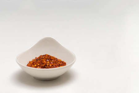 ceramic container with cayenne pepper flakes with copy space on white background food and spices conceptの写真素材