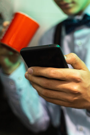 selective focus of a mobile phone used by a young man to send messages over the internet before...