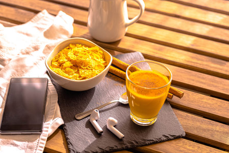 selective focus Breakfast on wooden table with mobile phone headset with golden milk food with...