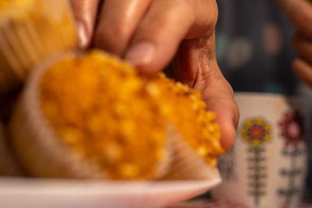 selective focus of a hand holding a delicious homemade muffin with chopped almond ready for...