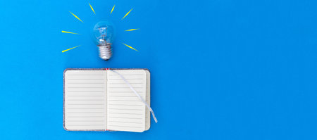 notebook with a light bulb with illuminated lines as a sign of ideas to write down on a blue...