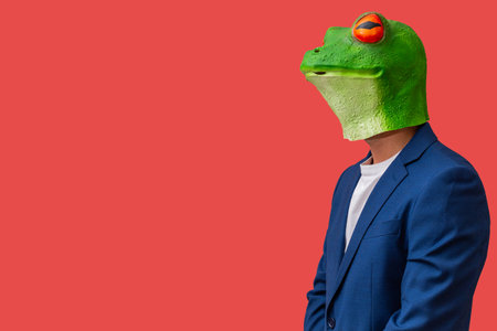 man in frog mask with bulging eyes staring and posing on red background with copy spaceの写真素材