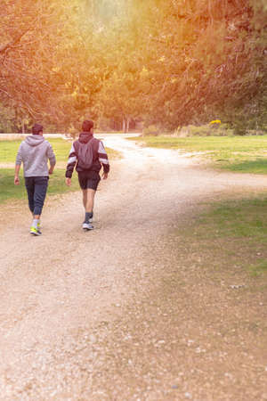 Two young teenagers walking along a rural rocky trail on a sunny evening hiking concept selective focusの写真素材