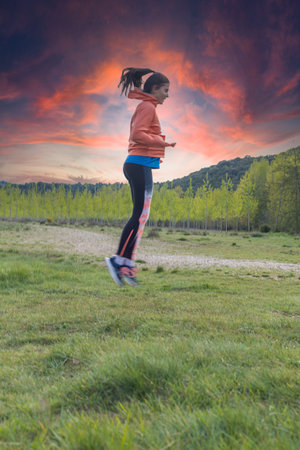 young teenager in sports clothes jumping in the middle of the field and performing training routines...