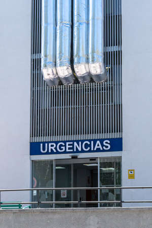 BURGOS, SPAIN - May 24, 2021: Main ER entrance at Recoletas Hospital in Burgos with blue sign in Spanish "URGENCIAS" (EMERGENCY) with heating and ventilation tubes above.のeditorial素材