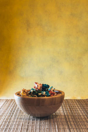 bamboo wood bowl with colorful sweet popcorn with yellow background and top copy spaceの写真素材