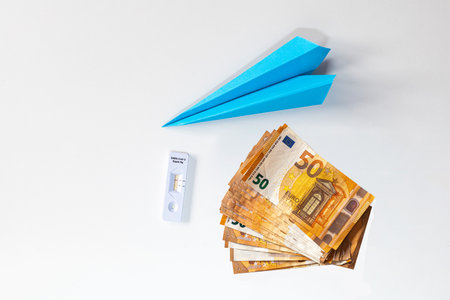 blue paper airplane with antigen test for  and a pile of tickets fanned out on a white background concept travel expenses tourism with copy spaceの写真素材