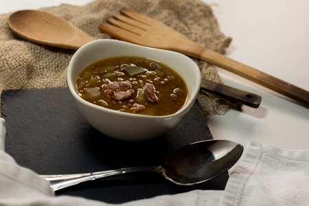 Plate of lentils with potatoes, leeks and chorizo typical of Spain on a black slate tray with traditional wooden cutlery with selective focus.の写真素材