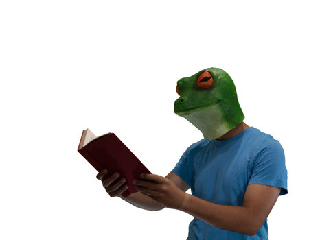 man with an animal mask of a frog on his head enjoying reading a book on a white background and copy spaceの写真素材
