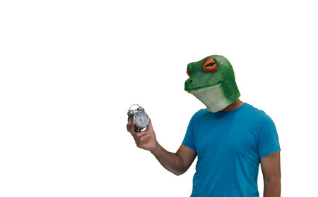 man with an animal mask of a frog on his head with an analog alarm clock with selective focus bells...
