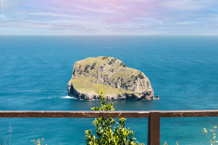 view from a viewpoint with a wooden fence of the cantabric sea and the island of Aquech or Aqueche island from bilbao and near San Juan de Gastelugaxe tourist place of Spain on a summer day.の写真素材