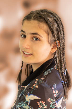 portrait of a smiling young teenage girl with long hair with many braids looking at the camera with out of focus background.の写真素材