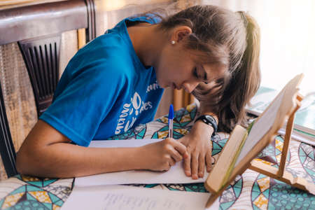 caucasian teenage girl with long hair in a ponytail studying at home and doing school homework for an exam or to make up failed subjects concpeto studyingの写真素材