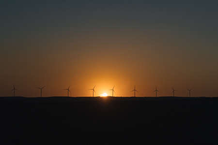 line of windmills in the sunset creating a yellowish backlight with selective focus concept clean renewable energy ecologyの写真素材