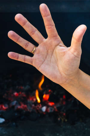 detail of a hand with the stop gesture when preparing a fire for a barbecue on a windy and sunny day with selective spotlighting fire hazard conceptの写真素材