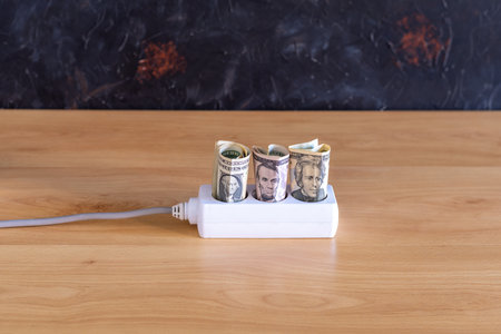 line of sockets with rolled dollar bills money on the floor concept money electricityの写真素材