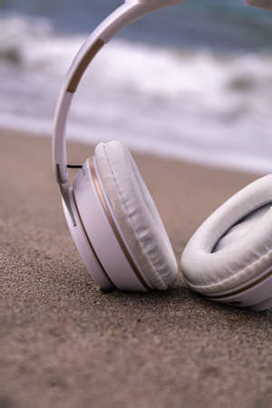 detail of a white wireless headphones on the sand of the beach with selective focus concept relax rest and rest relaxationの写真素材