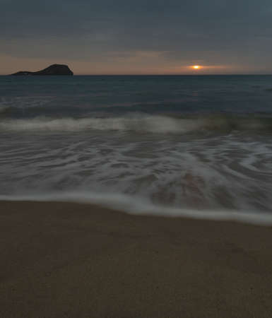 sunrise on the beach with silky water and sun in the backgroundの写真素材
