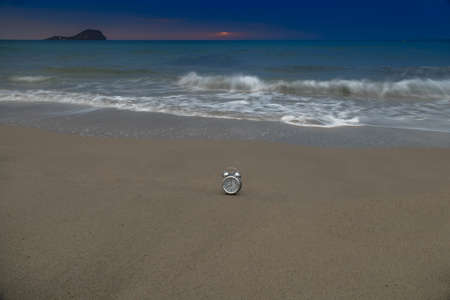 clock on the shore of the beach at sunrise with copy space concept blue hourの写真素材