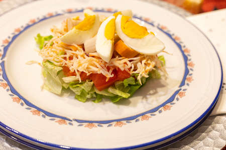 Healthy salad with lettuce cut on the bottom with tomato, seafood and boiled egg for a holiday in a restaurant with selective focus.の写真素材